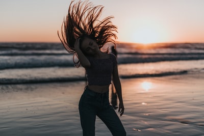 女人翻转头发在海滨日落
